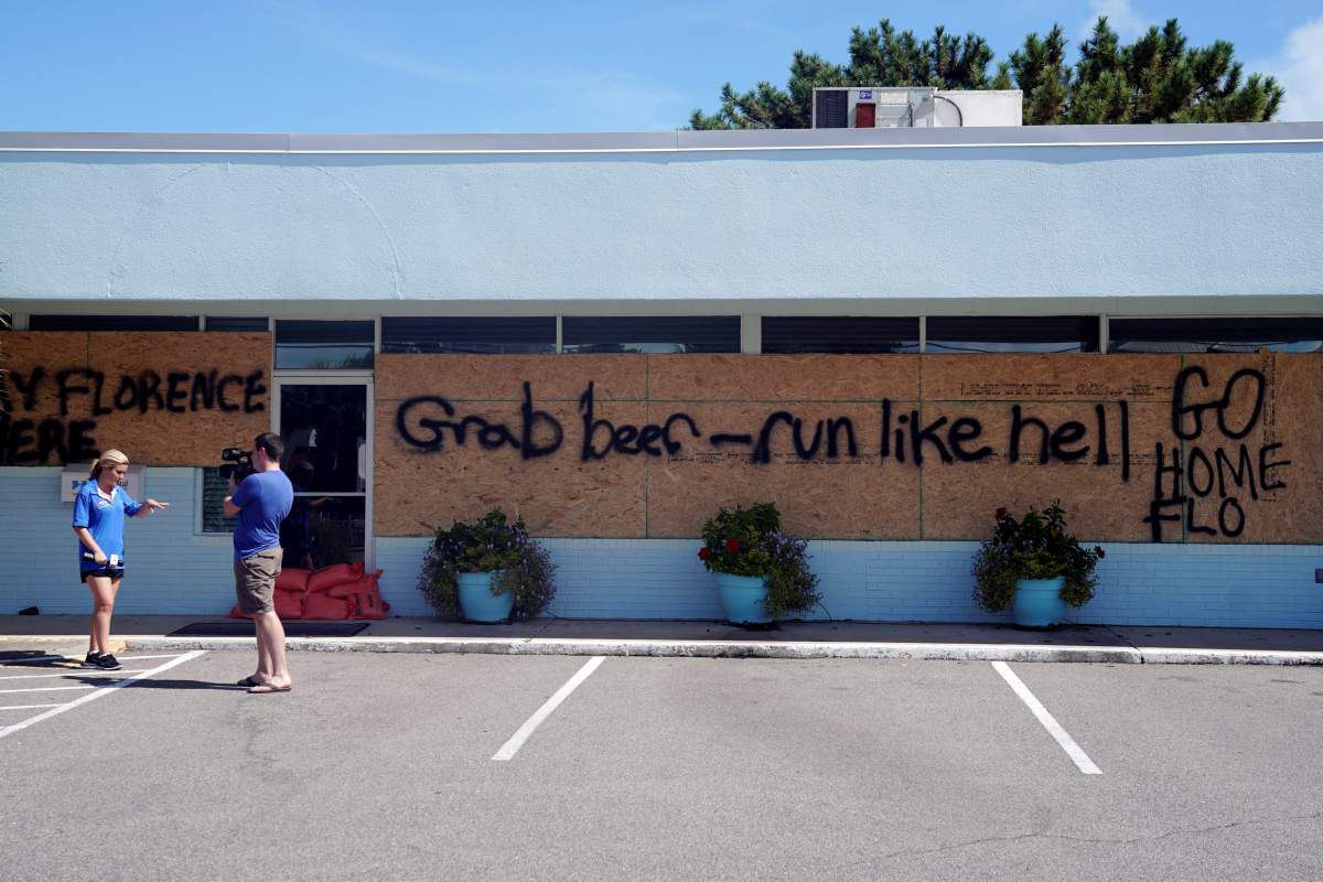 A reporter works on her story in front a boarded up store before Hurricane Florence comes ashore in Wrightsville Beach, North Carolina, U.S., September 12, 2018.