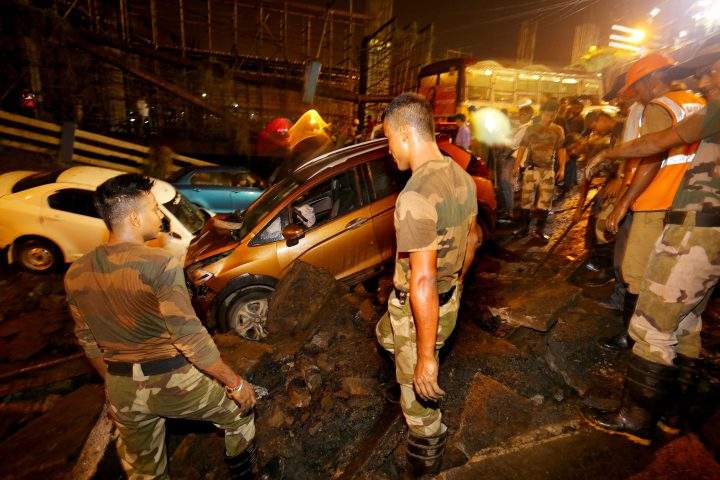 People gather while National Disaster Response Force (NDRF) and Indian army personnel work at the site of a collapsed bridge in Kolkata, Eastern India, on Sept. 4, 2018.