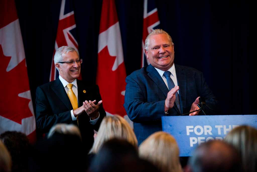Finance Minister Vic Fedeli applauds alongside Premier Doug Ford after speaking to members of his caucus in Toronto on Monday, Sept. 24, 2018. 