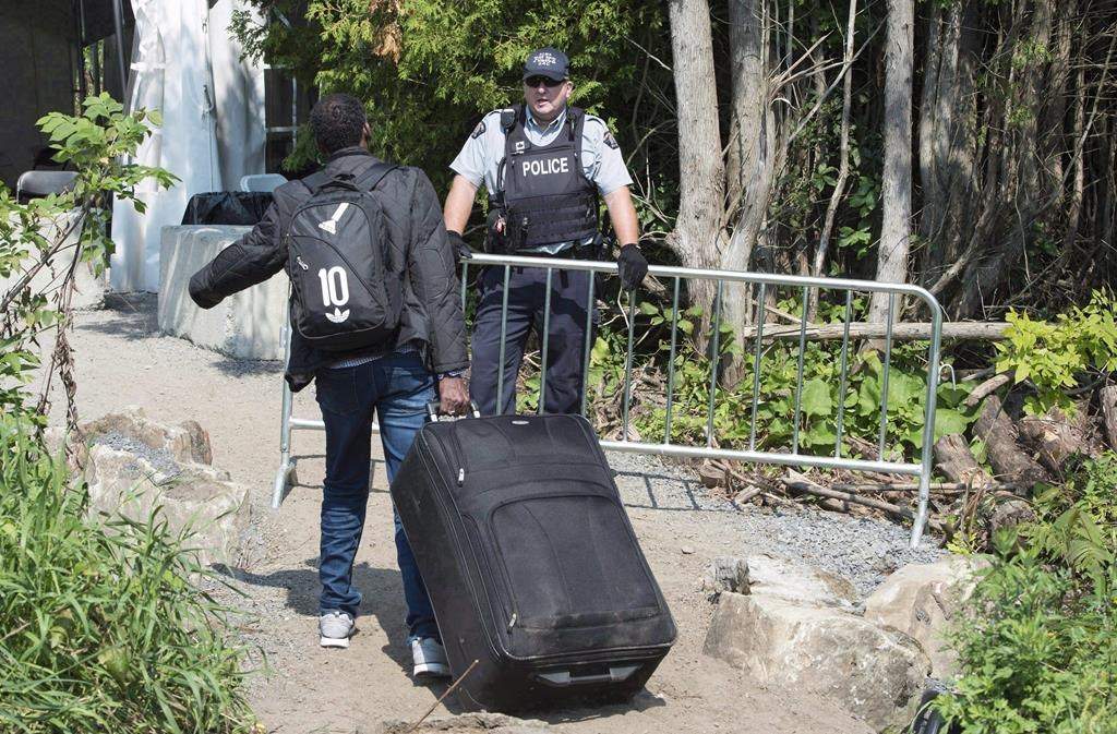 An asylum seekers, claiming to be from Eritrea, is confronted by an RCMP officer as he crosses the border into Canada from the United States on August 21, 2017 near Champlain, N.Y.