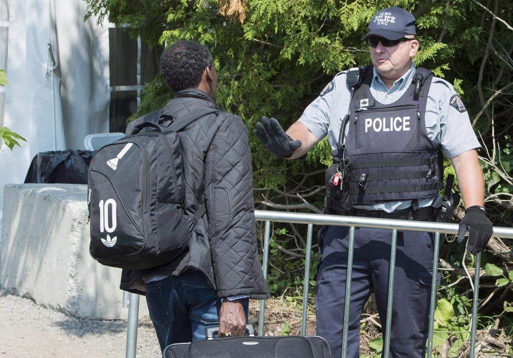 An asylum seeker is questioned by an RCMP officer as he crosses the border into Canada from the United States Monday, August 21, 2017 near Champlain, N.Y. Newly released figures show Canadian officials have removed only a handful of the hundreds of irregular migrants who were already under orders to be deported from the United States. THE CANADIAN PRESS/Paul Chiasson.