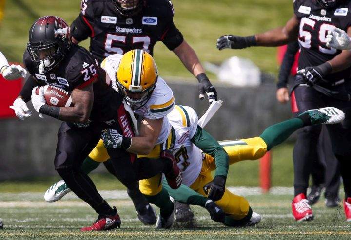 Edmonton Eskimos' players tackle Calgary Stampeders' Don Jackson during first half CFL football action in Calgary, Monday, Sept. 3, 2018.