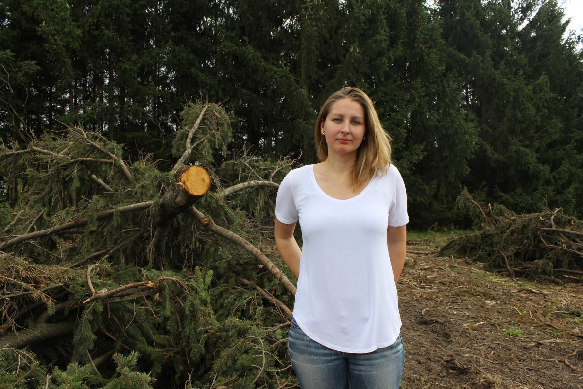 Jenna Goodhand stands before some of the trees that have already been bulldozed. In the background, you can see part of the row of trees she and other activists hope to protect.