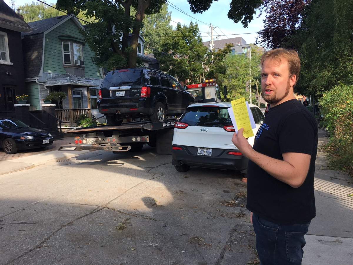 As his SUV is towed away with two slashed tires Rob Retchless holds the parking ticket he received for having the vehicle parked on his street overnight.