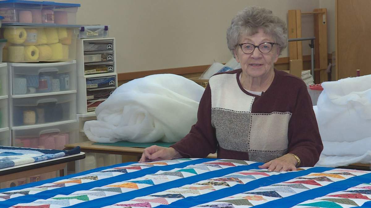 Vera Sexsmith inspects a large quilt to be sold at a charitable quilt sale.