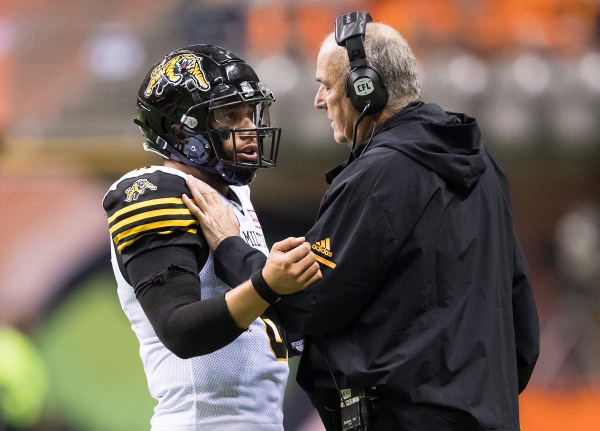 Hamilton Tiger-Cats quarterback Jeremiah Masoli, left, listens to head coach June Jones during a break during the second half of a CFL football game against the B.C. Lions in Vancouver, on Saturday September 22, 2018.