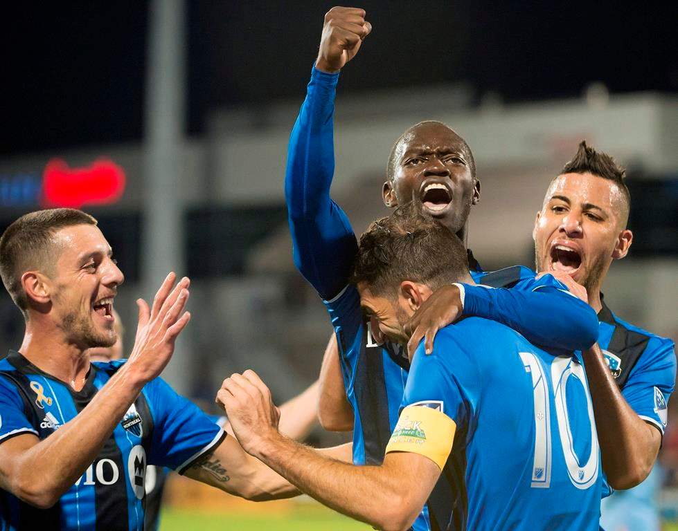 In this file photo, Montreal Impact's Micheal Azira, center, celebrates with teammates.