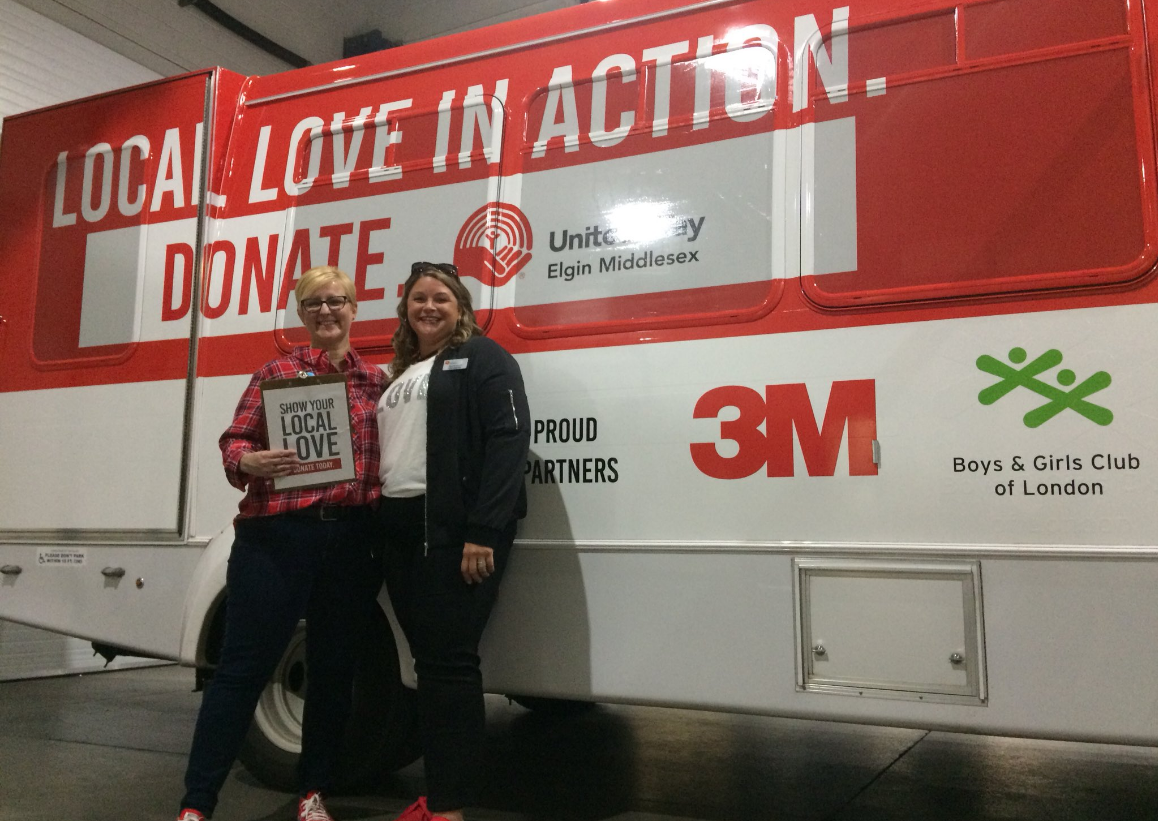 Kelly Ziegner, CEO of United Way of Elgin and Middlesex and Kyla Woodcock, the organization's 2018 campaign chair and first Chief ChangeMaker stand by the Local Love in Action bus at the 3M Harvest Lunch in London, Ont. on Sept. 20, 2018.