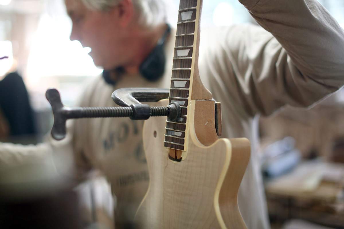 In this photo taken on March 25, 2015, a guitar neck is glued and clamped into an electric guitar body at the Heritage Guitar in Kalamazoo, Mich.