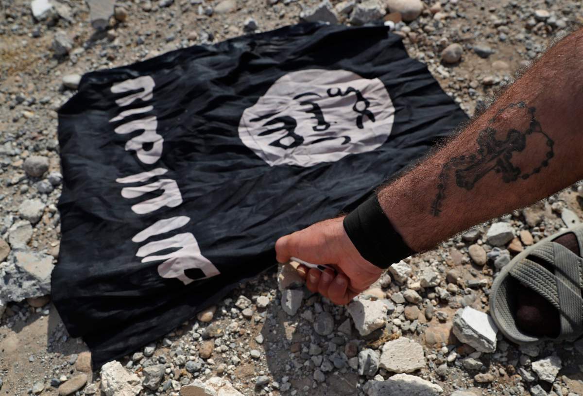 A Christian Syriac militia fighter burns an IS flag on the front line on the western side of Raqqa, northeast Syria, Monday, July 17, 2017. 