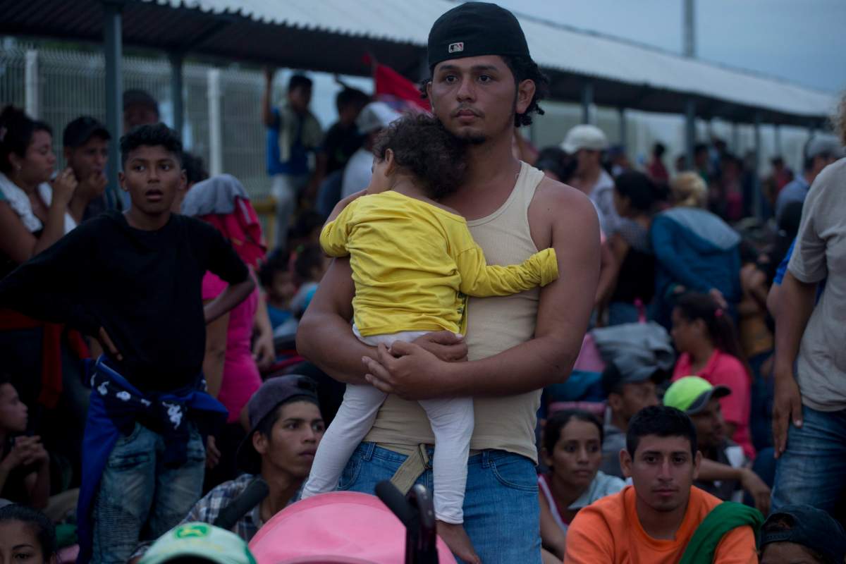 Migrants bound for the U.S.-Mexico border wait on a bridge that stretches over the Suchiate River, connecting Guatemala and Mexico, in Tecun Uman, Guatemala, Friday, Oct. 19, 2018.