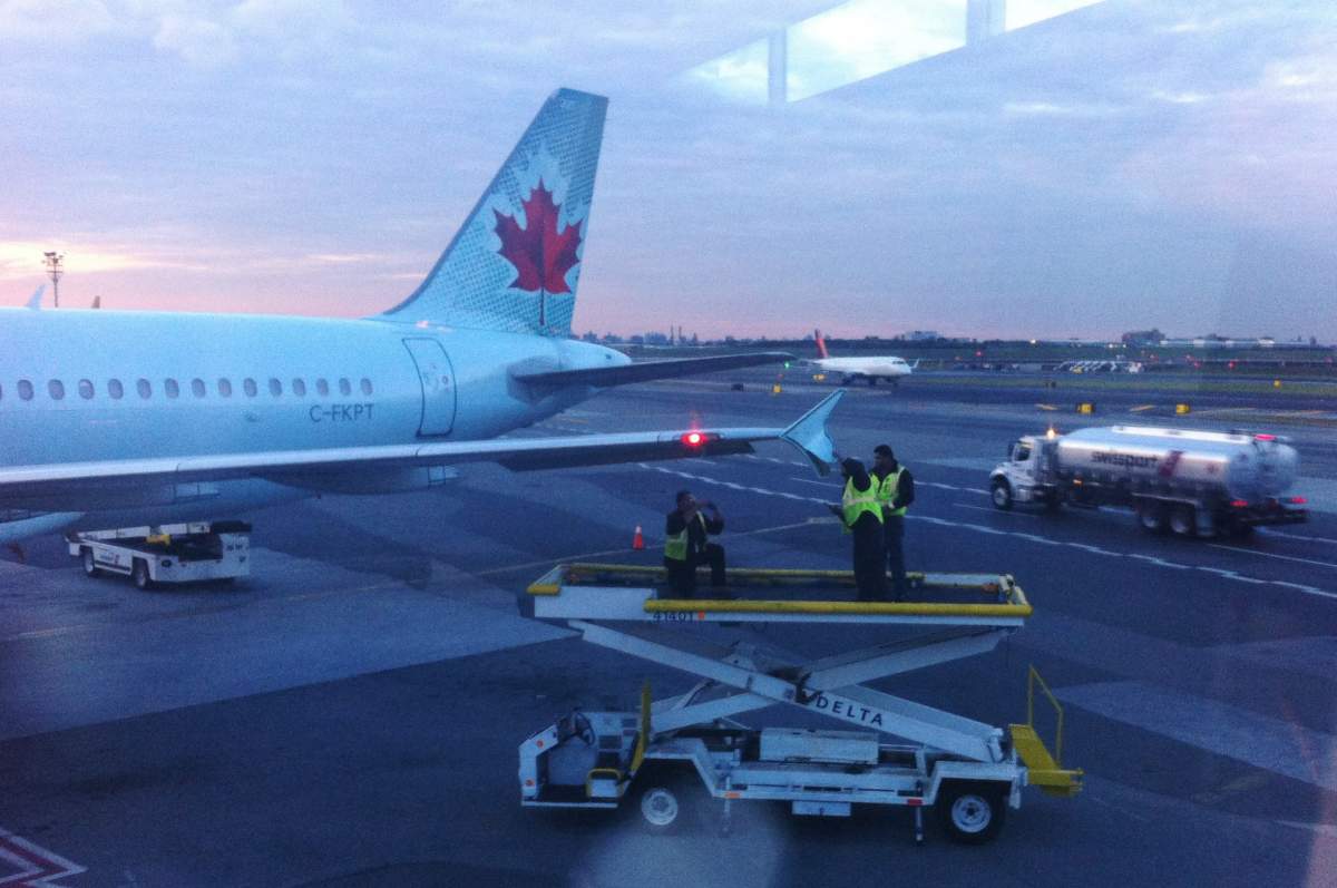Runway crew members examine the wing tip of an Air Canada plane which arrived at LaGuardia Airport in New York on Monday, Oct. 22, 2018. An Air Canada flight that had just landed at New York's LaGuardia Airport late Monday afternoon was damaged as it sat on the taxiway by another passing plane. New York Port Authority spokesman Rudy King says the Air Canada jet was stationary on the taxiway when an American Airlines plane that was attempting to turn clipped its wing. 