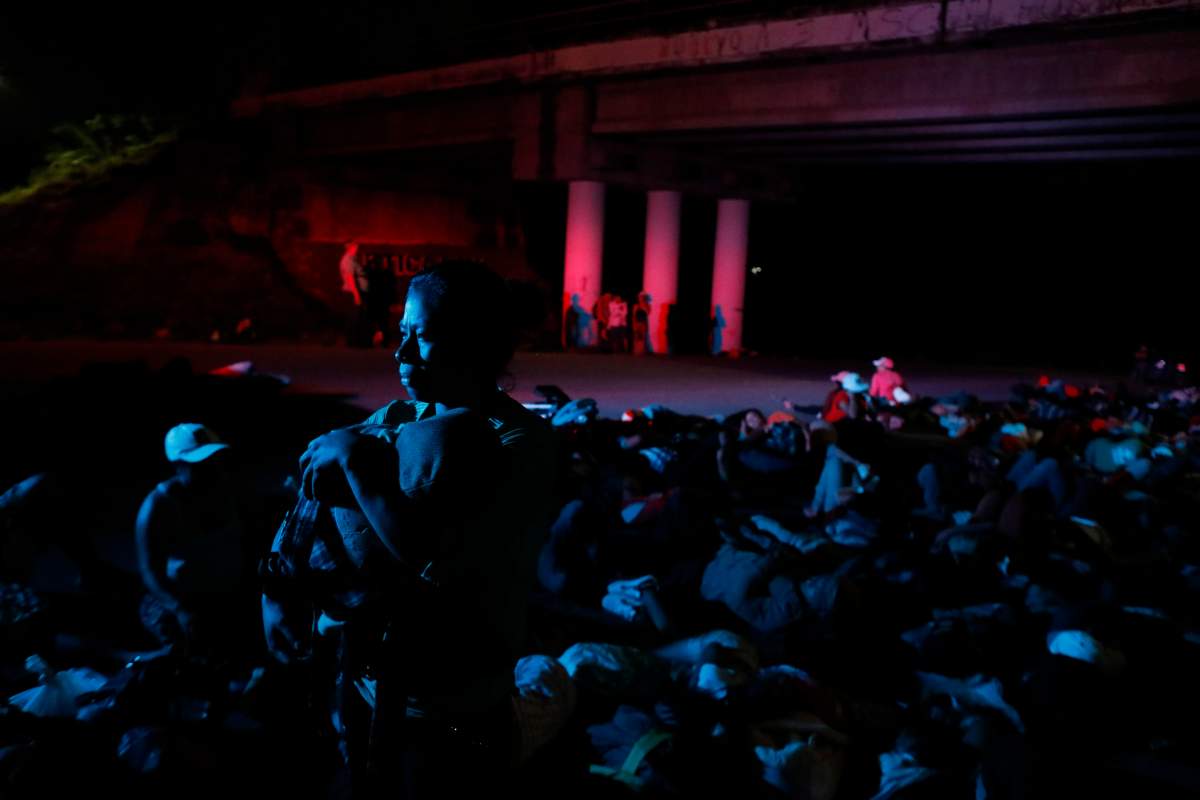 A woman holds her baby as she waits in hopes of a ride among other Central Americans participating in the thousands-strong caravan of Central American slowly making its way toward the U.S. border, outside Pijijiapan, Mexico, before dawn on Friday, Oct. 26, 2018. 