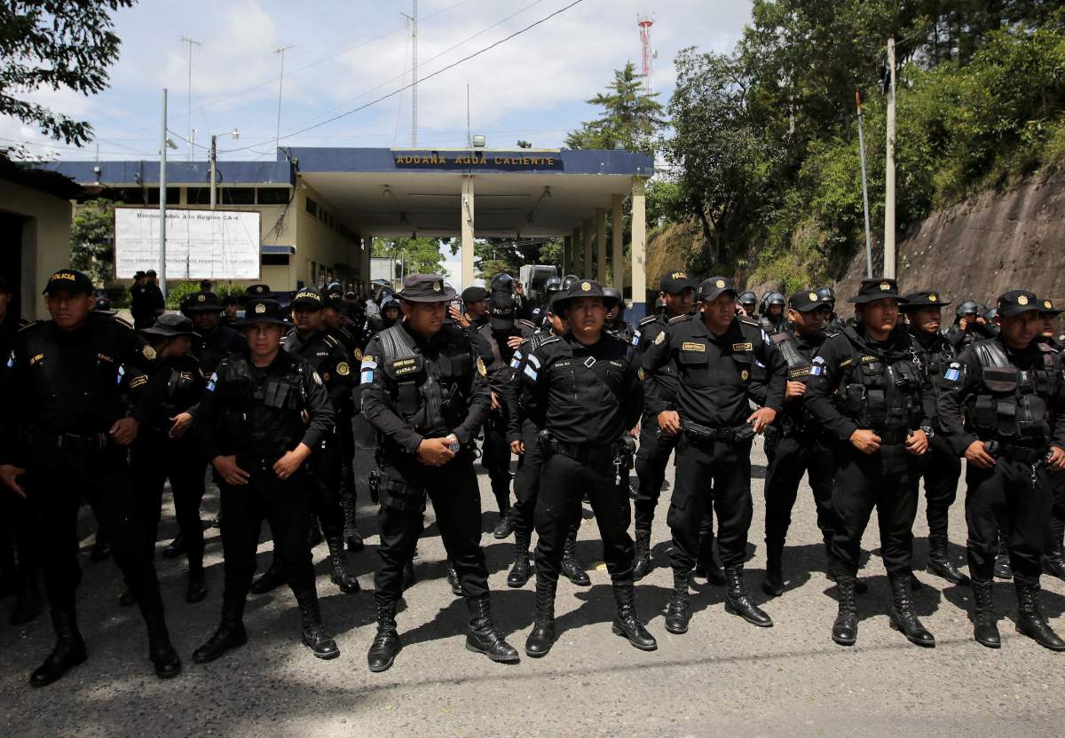 Guatemalan police officers stand as Honduran migrants, part of a caravan trying to reach the U.S., arrive at the border between Honduras and Guatemala.