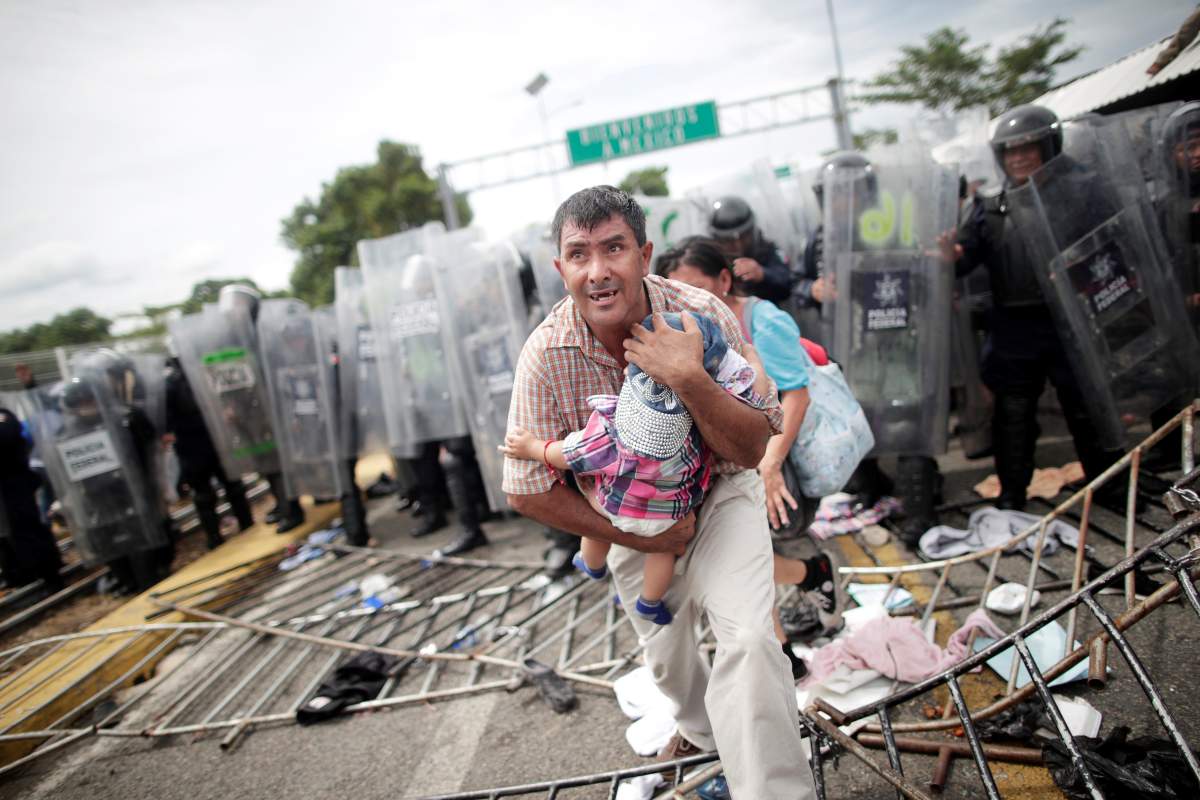 A Honduran migrant protects his child after fellow migrants, part of a caravan trying to reach the U.S., stormed a border checkpoint in Guatemala, in Ciudad Hidalgo, Mexico October 19, 2018. REUTERS/Ueslei Marcelino