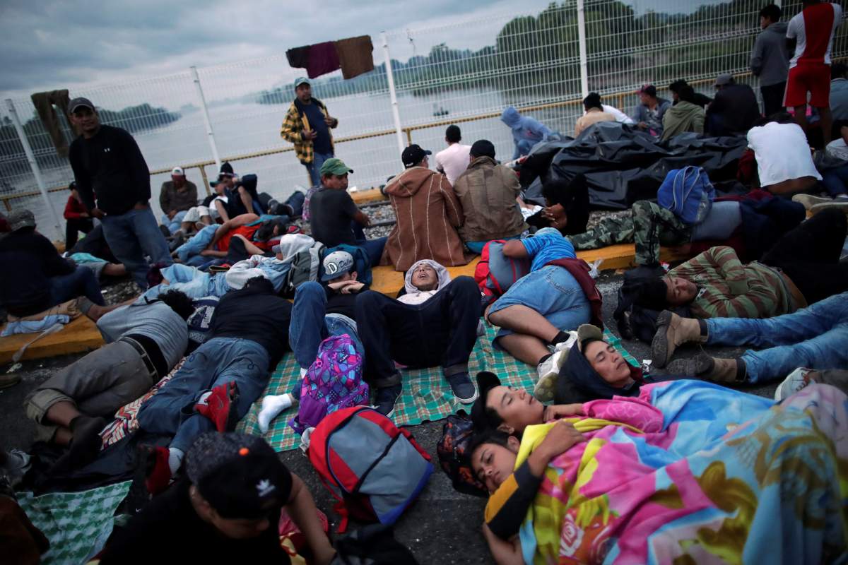 Honduran migrants, part of a caravan trying to reach the U.S., wait to open the gate on the bridge that connects Mexico and Guatemala.