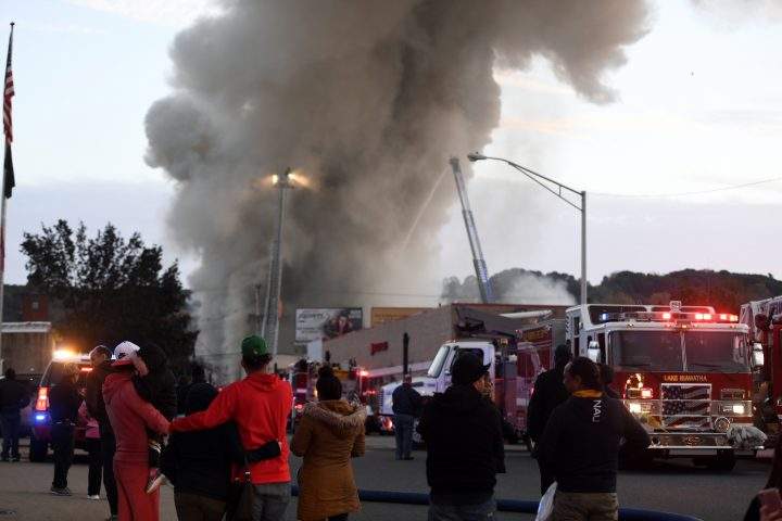 People watch from the street as firefighters respond to a seven-alarm fire on Monday, Oct. 22, 2018 in Dover, N.J.