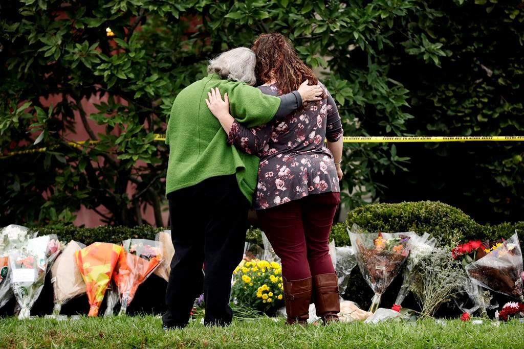 Two people support each other in front of flowers at a makeshift memorial at the Tree of Life Synagogue in Pittsburgh, Sunday, Oct. 28, 2018. Robert Bowers, the suspect in Saturday's mass shooting at the synagogue, expressed hatred of Jews during the rampage and told officers afterward that Jews were committing genocide and he wanted them all to die, according to charging documents made public Sunday. THE CANADIAN PRESS/AP-Matt Rourke.