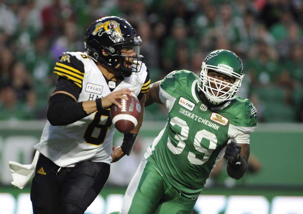 Hamilton Tiger-Cats quarterback Jeremiah Masoli, left, is chased by Saskatchewan Roughriders defensive lineman Charleston Hughes on Thursday, July 5, 2018.