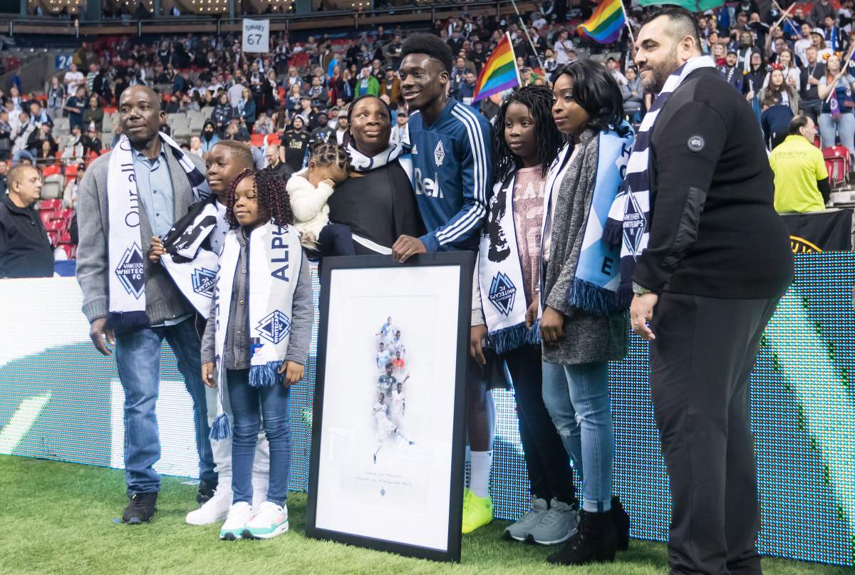 Vancouver Whitecaps midfielder Alphonso Davies, centre, poses for photographs with family members after being honoured before playing his final match as a member of the Vancouver Whitecaps.
