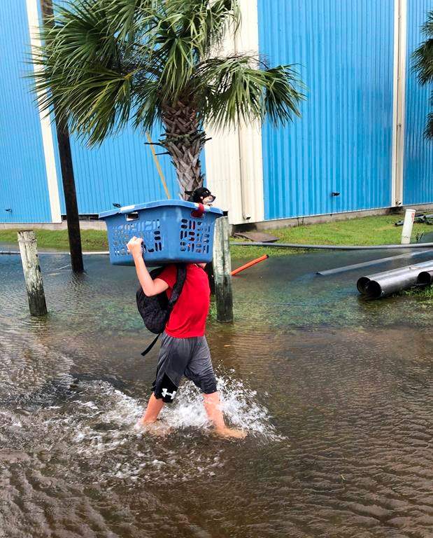 Jayden Morgan carries his dog through a flooded street in St. Marks, Fla., on Wednesday, Oct. 10, 2018, as his family evacuates at the last minute before Hurricane Michael hits the state. (AP Photo/Brendan Farrington)