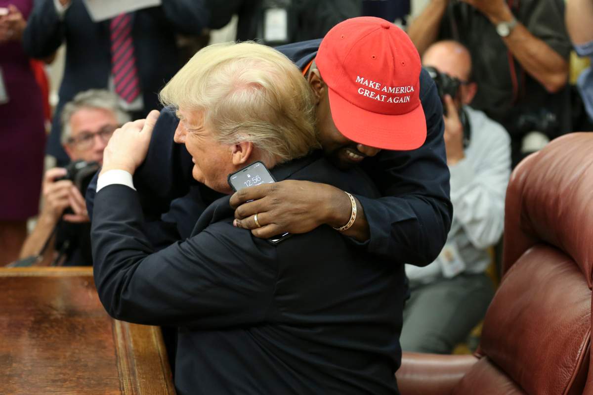 U.S. President Donald Trump hugs rapper Kanye West during a meeting in the Oval office of the White House on October 11, 2018 in Washington, DC. (Photo by Oliver Contreras – Pool/Getty Images)