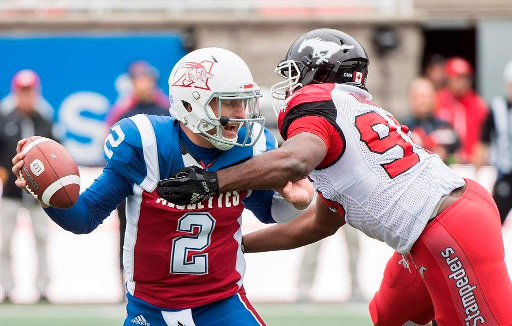 Montreal Alouettes quarterback Johnny Manziel, left, evades a tackle by Calgary Stampeders' Ja'Gared Davis during first half CFL football action in Montreal, Monday, October 8, 2018.
