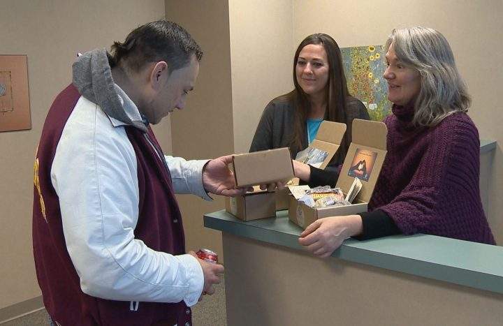 Kayla Johnson (middle), with CMHA Calgary, and Karen Pickes, Stresscase co-founder, and D.B. Thunderchild inspect SOS Kits.