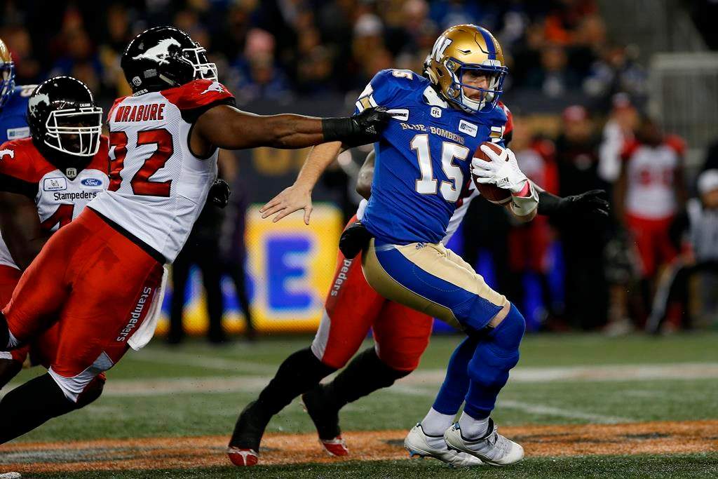 Winnipeg Blue Bombers quarterback Matt Nichols (15) attempts to get out of the grasp of Calgary Stampeders' Ese Mrabure (92) during the first half of CFL action in Winnipeg, Friday, Oct. 26, 2018.