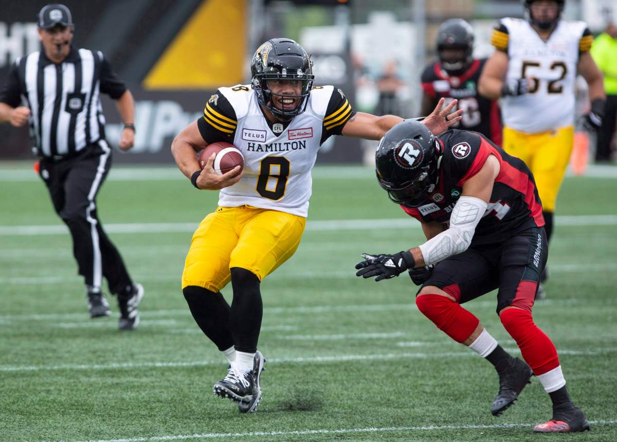Hamilton Tiger-Cats quarterback Jeremiah Masoli (8) tries to fend off Ottawa Redblacks Anthony Cioffi during second half CFL football game action in Hamilton, Ont. on Saturday, July 28, 2018.