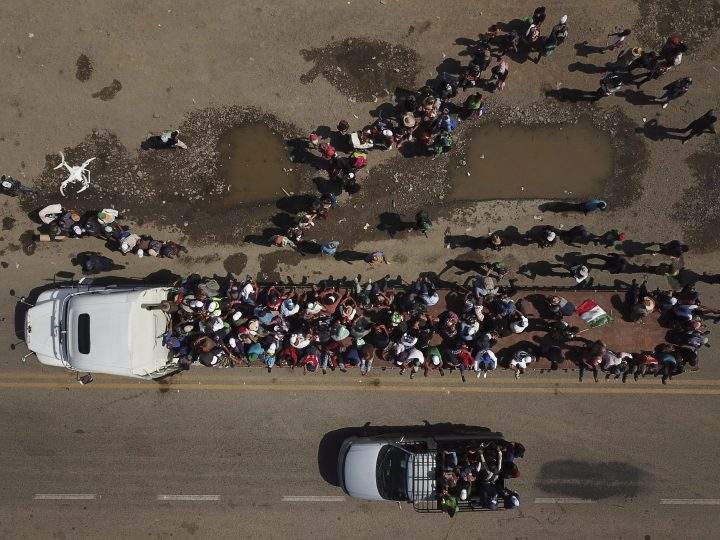 Migrants climb on the trailer of a truck as others wait in a line for a ride on the road that connects Tapanatepec with Niltepec, Mexico, as a caravan of Central Americans continues its slow march toward the U.S. border, Monday, Oct. 29, 2018.