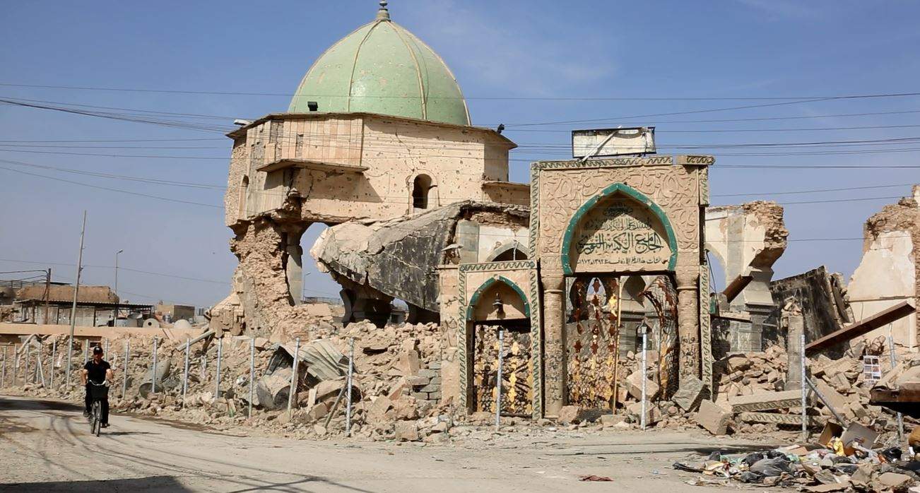 An Iraqi on a motorcycle drives past destroyed buildings in the city of Mosul.
