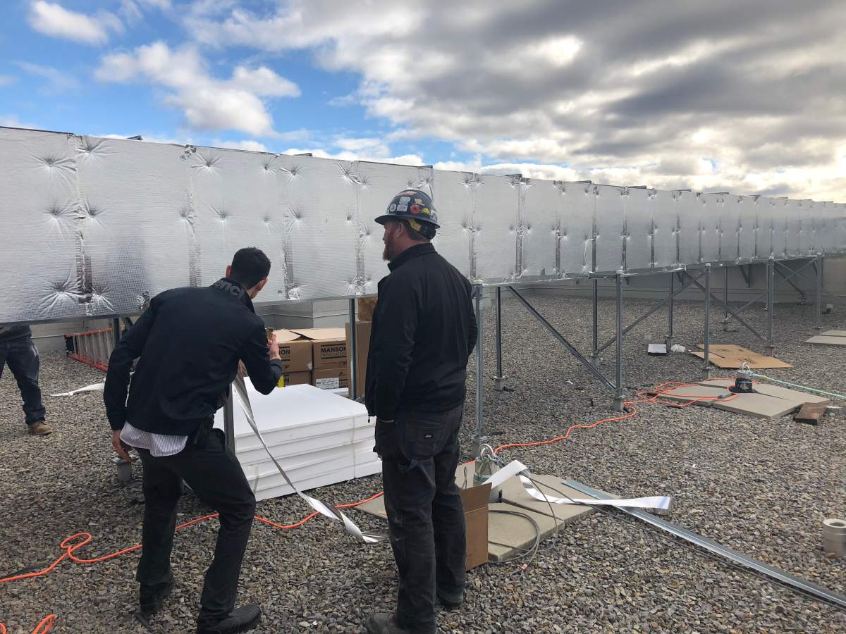 Workers install insulation onto an updated solar heating duct at an OCH apartment building at 1455 Clementine Ave. on Wednesday morning.