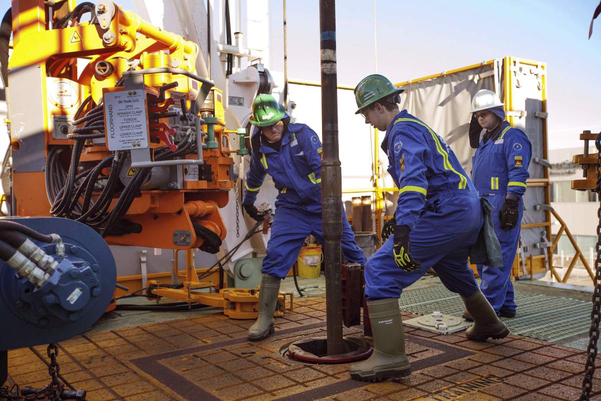 Trainees Dan Brook and Bradley Williams are directed by instructor Clint Dyck while training to lay down drill pipe on a rig floor, at Precision Drilling in Nisku, Alta., on January 20, 2016. 