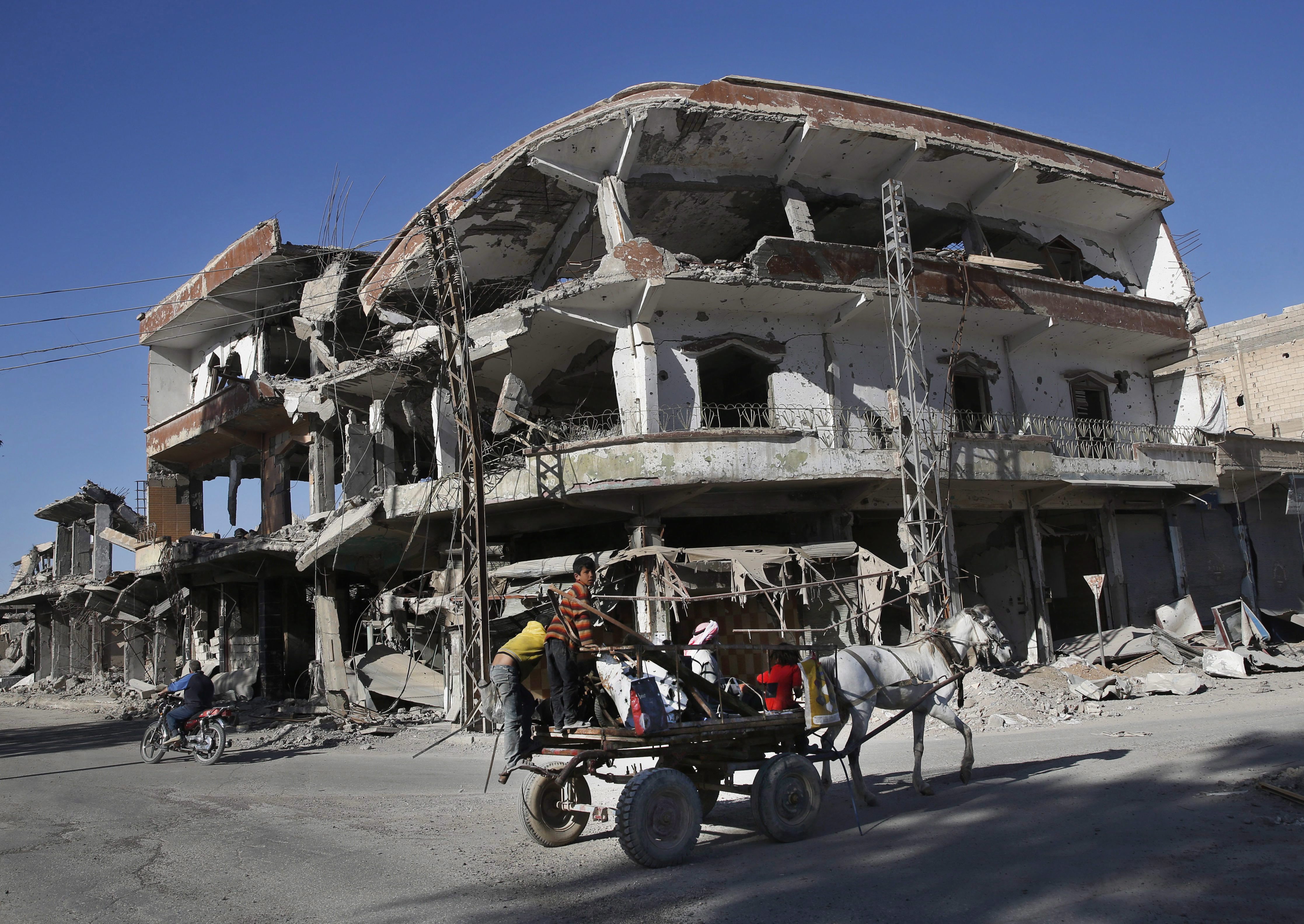 In this Thursday, April 5, 2018 photo, the remains of buildings line a street that was damaged last summer during fighting between U.S.-backed Syrian Democratic Forces fighters and Islamic State militants, in Raqqa, Syria.