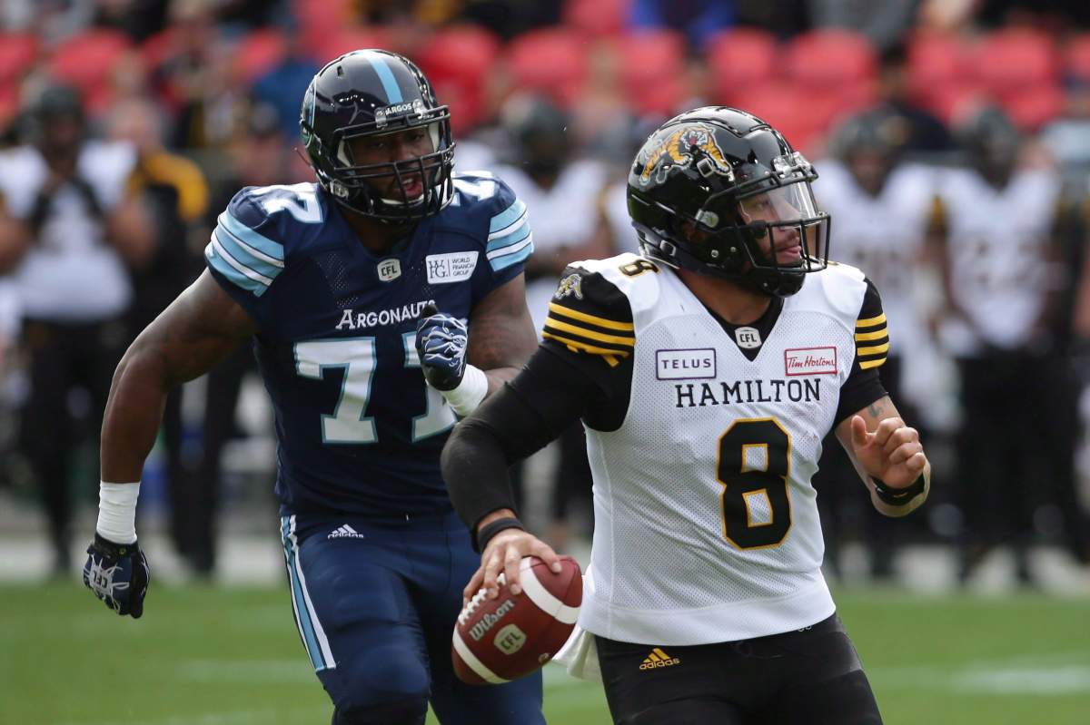 Toronto Argonauts defensive end Rakim Cox (77) chases down Hamilton Tiger-Cats quarterback Jeremiah Masoli (8) during second half CFL football action, in Toronto, Saturday, Sept. 8, 2018.