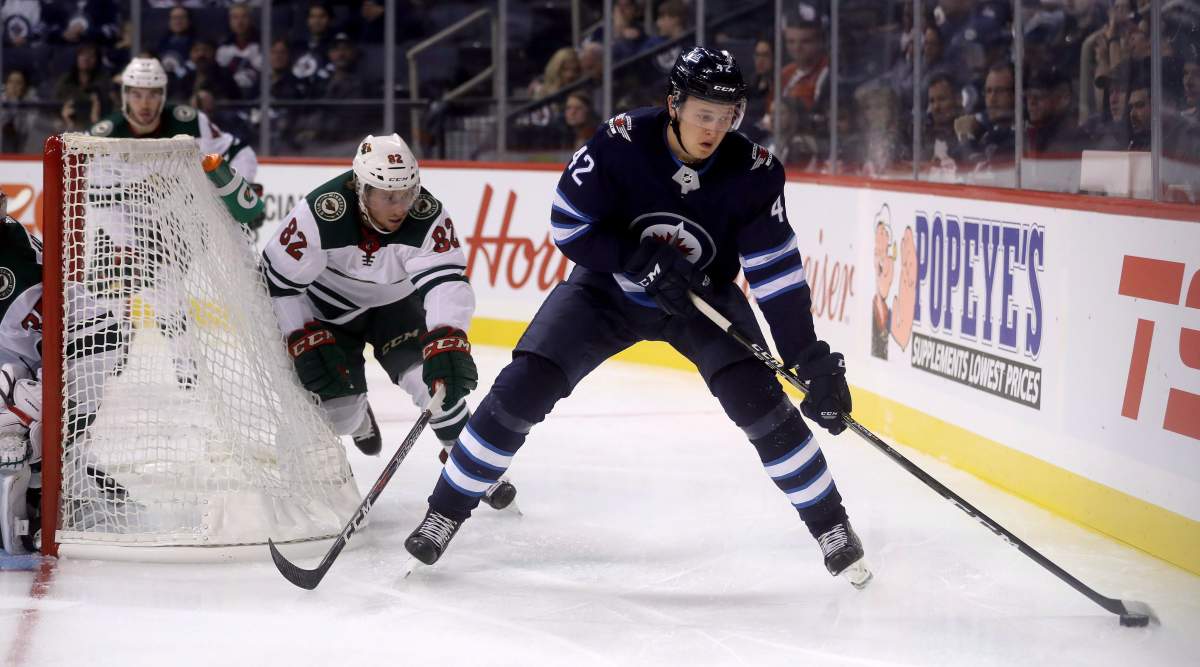 The Winnipeg Jets’ Kristian Vesalainen (42) carries the puck in front of the Minnesota Wild’s Justin Kloos (82) behind the Minnesota goal during second-period pre-season NHL hockey in Winnipeg, Monday, Sept. 17, 2018. THE CANADIAN PRESS/Trevor Hagan