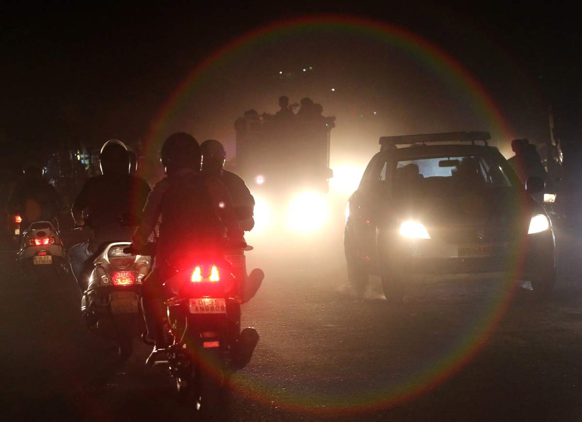 Indian people commute on motorcycles and cars through heavy dust and smog in New Delhi, India, Oct. 19, 2018.