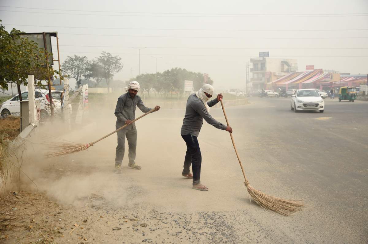 Dust rises as municipal workers use brooms to sweep a road on a foggy day in Greater Noida, near New Delhi, India, Monday, Nov. 5, 2018.