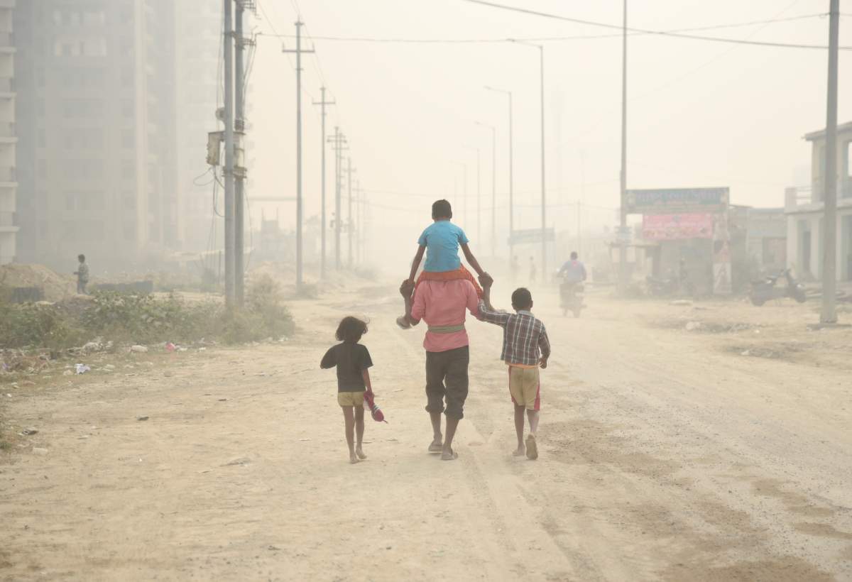 A village man walks carrying a child on his shoulders on a foggy day in Greater Noida, near New Delhi, India, Monday, Nov. 5, 2018.