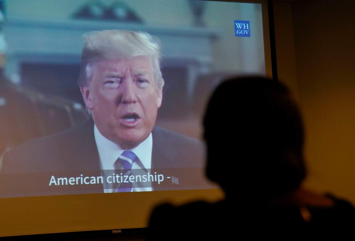 Maria Valles Bonilla, right, watches a taped video message from President Donald Trump after taking the Oath of Allegiance during a naturalization ceremony at U.S. Citizenship and Immigration Services office Tuesday, Nov. 6, 2018, in Fairfax, Va.