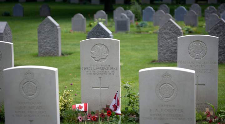 In this file photo taken on Saturday, July 26, 2014, wooden crosses and Canadian flags adorn the grave of World War I Canadian soldier Pvt. George Lawrence Price, center, at the St. Symphorien Cemetery near Mons, Belgium.