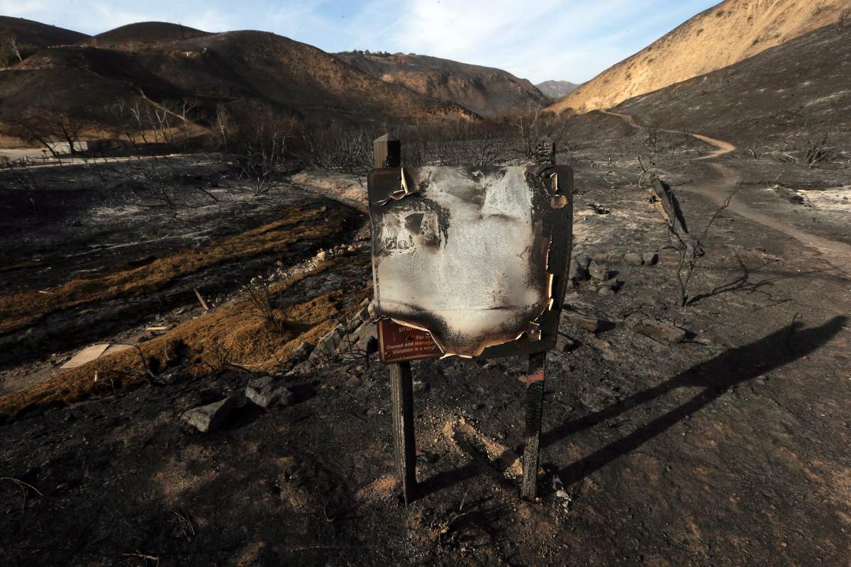 In this Tuesday, Nov. 13, 2018 photo, a sign designating the Corral Canyon Park recreation area stands amid landscape charred by the Woolsey fire in Malibu, Calif. The Woolsey fire has charred more than 83 percent of National Park Service land within the Santa Monica Mountain National Recreational Area. Officials announced Wednesday, Nov. 14, 2018, that all trails were closed.