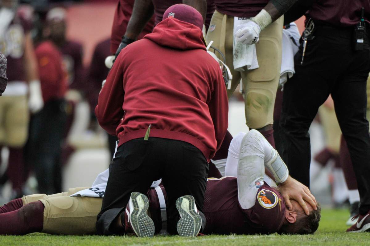 Washington Redskins quarterback Alex Smith, bottom, reacts after an injury during the second half of an NFL football game against the Houston Texans, Sunday, Nov. 18, 2018, in Landover, Md.
