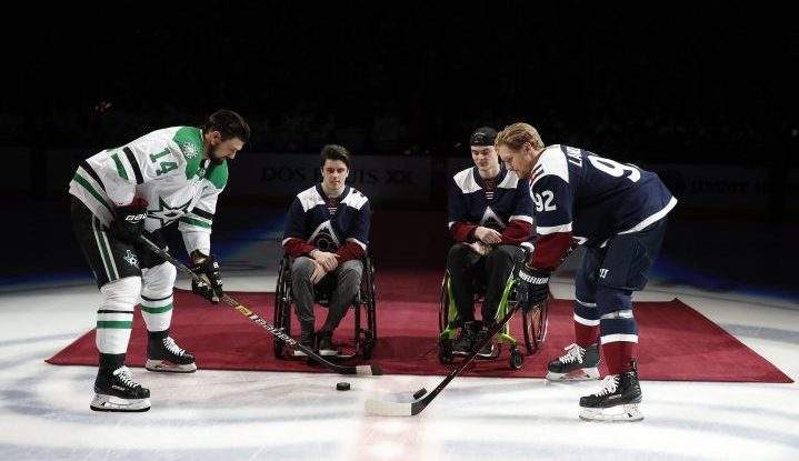 At left, Dallas Stars left wing Jamie Benn takes part in a ceremonial puck drop with Colorado Avalanche left wing Gabriel Landeskog, right, by two players from the Humboldt Broncos, Ryan Straschnitzki, second from left, and Jacob Wassermann, to open an NHL hockey game Saturday, Nov. 24, in Denver.