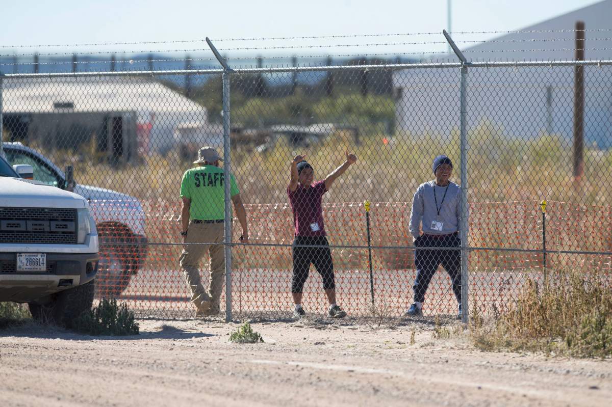 In this Nov. 15, 2018 photo provided by Ivan Pierre Aguirre, migrant teens held inside the Tornillo detention camp smile at protestors waving at them outside the fences surrounding the facility in Tornillo, Texas.