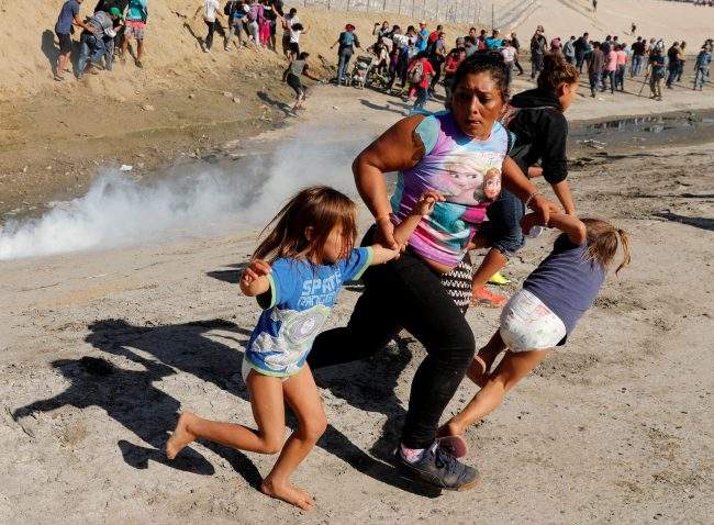 A migrant family from Honduras, part of a caravan of thousands traveling from Central America en route to the United States, runs from tear gas released by U.S. border patrol near the fence between Mexico and the United States in Tijuana, Mexico, Nov. 25, 2018.