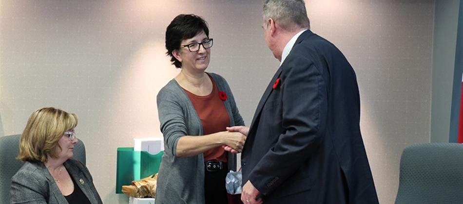 New Louis Riel School Division board chair Sandy Nemeth shakes hands with her predecessor, Chris Sigurdson.