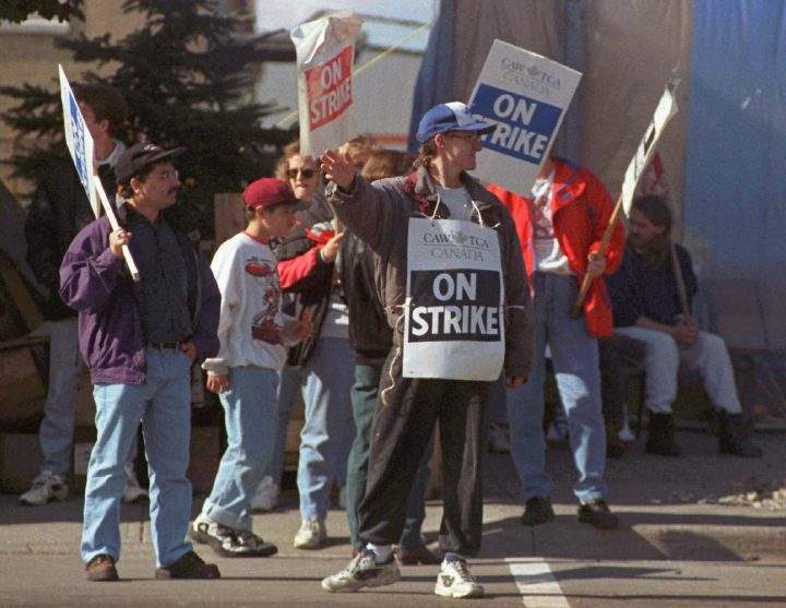 Striking General Motors worker Peter Gualandris, centre, waves to passing motorists outside the GM Oshawa plant on Oct. 6, 1996.