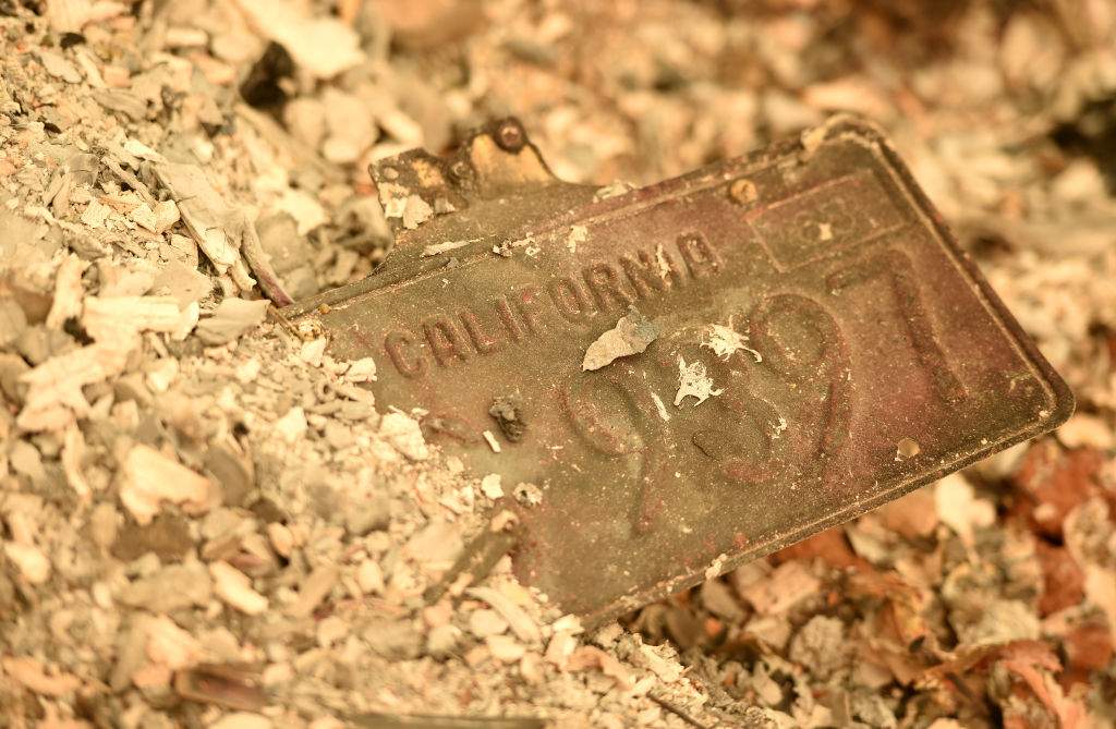A California license plate is seen partially buried in a pile of ash at a burned residence after the Camp fire tore through the region in Paradise, California on November 12, 2018.